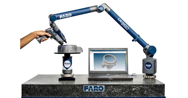 Portable articulated CMM arm inspecting a component beside a laptop