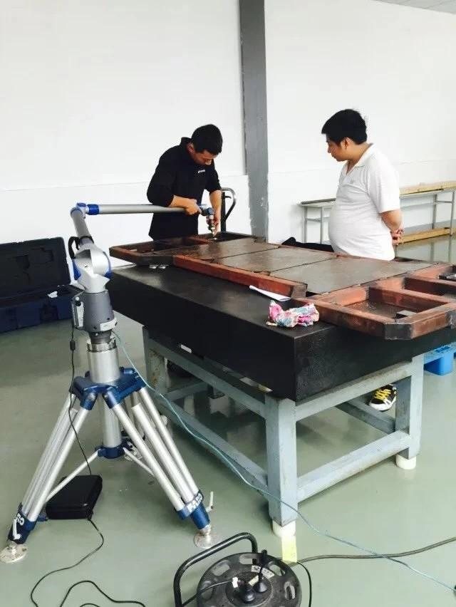 Technician 3D scanning a large steel fixture on a granite table